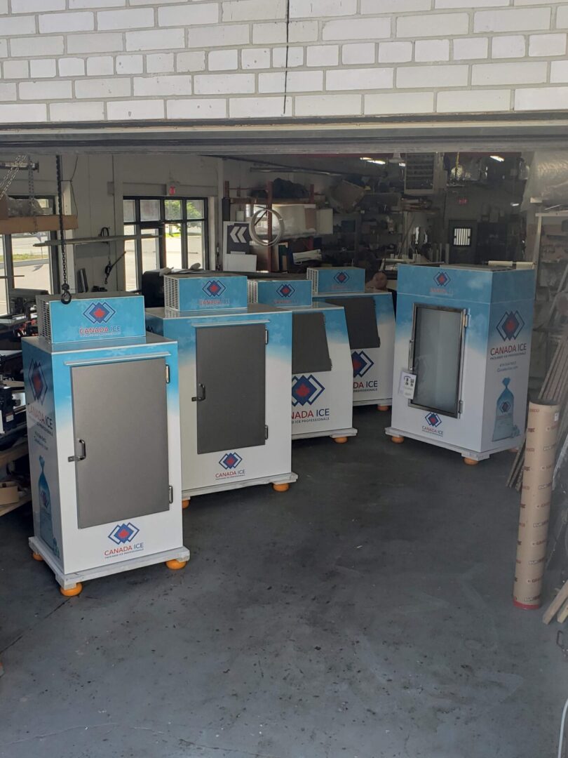 A group of refrigerators in a room with windows.